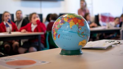 a globe in the foreground, with students in the background, blurred