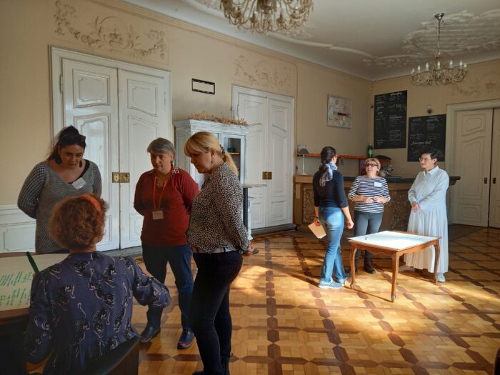 Individuals participating in an activity in groups. Two groups visible. Some sitting, most standing.